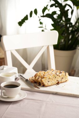 Geleneksel Alman noel pastası mermer kesim tahtasına, kahve fincanına, masa örtüsüne tereyağı tabağına ve arka taraftaki skandal tarzı mutfak sandalyesine çalınmış.