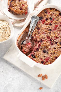 breakfast casserole idea - oven berry baked oatmeal in a white porcelain baking form on a marble board, top view