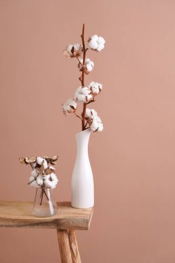several branches with white cotton plant in white vase - autumn decoration on beige colored background,close up, negative space