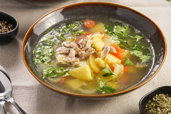 stock image two deep green bowls with traditional european chicken soup with potato, carrots, celery, fresh parsley on a beige colored kitchen table cloth