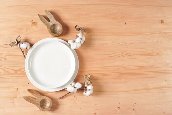 stock image A top view on a Empty white ceramic plate, cotton flower decoration on a wooden background, copy space, top view