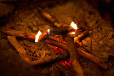 A cozy fire made from several wooden rods, creating an atmosphere of warmth and comfort in nature clipart