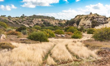 Kıbrıs Rum Kesimi 'nin berrak gökyüzü, az bulut ve sınırlı bitki örtüsü ile manzaralı sakin bir fotoğraf, adanın doğal güzelliğini gösteriyor