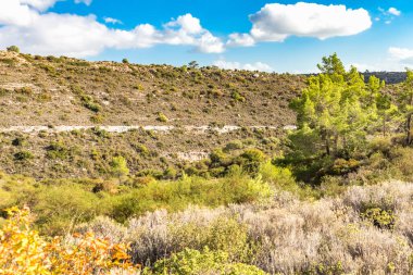 Kıbrıs Rum Kesimi 'nin berrak gökyüzü, az bulut ve sınırlı bitki örtüsü ile manzaralı sakin bir fotoğraf, adanın doğal güzelliğini gösteriyor