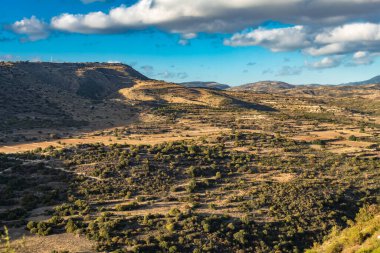 Kıbrıs Rum Kesimi 'nin berrak gökyüzü, az bulut ve sınırlı bitki örtüsü ile manzaralı sakin bir fotoğraf, adanın doğal güzelliğini gösteriyor