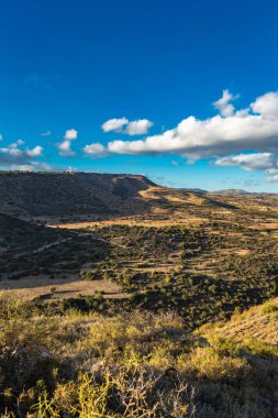 Kıbrıs Rum Kesimi 'nin berrak gökyüzü, az bulut ve sınırlı bitki örtüsü ile manzaralı sakin bir fotoğraf, adanın doğal güzelliğini gösteriyor
