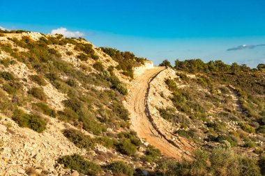 Kıbrıs Rum Kesimi 'nin berrak gökyüzü, az bulut ve sınırlı bitki örtüsü ile manzaralı sakin bir fotoğraf, adanın doğal güzelliğini gösteriyor