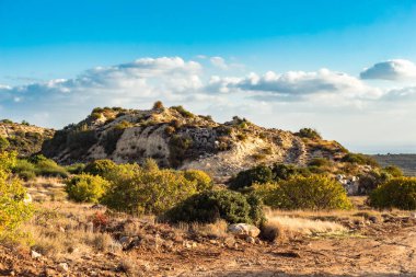Kıbrıs Rum Kesimi 'nin berrak gökyüzü, az bulut ve sınırlı bitki örtüsü ile manzaralı sakin bir fotoğraf, adanın doğal güzelliğini gösteriyor