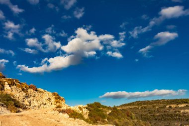 Kıbrıs Rum Kesimi 'nin berrak gökyüzü, az bulut ve sınırlı bitki örtüsü ile manzaralı sakin bir fotoğraf, adanın doğal güzelliğini gösteriyor