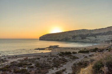 Kıbrıs 'taki Zapallo Körfezi Sahili' nde büyüleyici bir gün batımı, alacakaranlık batışı, dağın arkasında güneş batışı, çarpıcı bir akşam manzarası.