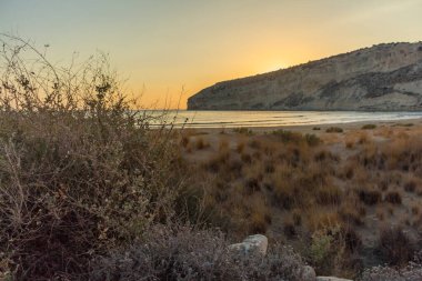 Kıbrıs 'taki Zapallo Körfezi Sahili' nde büyüleyici bir gün batımı, alacakaranlık batışı, dağın arkasında güneş batışı, çarpıcı bir akşam manzarası.