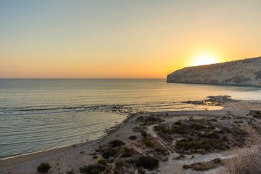 Kıbrıs 'taki Zapallo Körfezi Sahili' nde büyüleyici bir gün batımı, alacakaranlık batışı, dağın arkasında güneş batışı, çarpıcı bir akşam manzarası.
