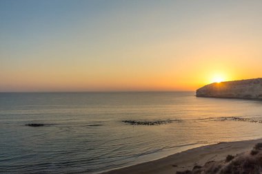 Kıbrıs 'taki Zapallo Körfezi Sahili' nde büyüleyici bir gün batımı, alacakaranlık batışı, dağın arkasında güneş batışı, çarpıcı bir akşam manzarası.