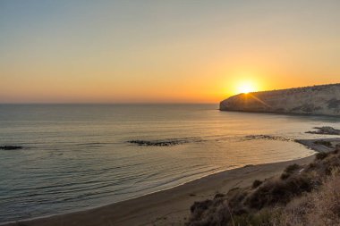 Kıbrıs 'taki Zapallo Körfezi Sahili' nde büyüleyici bir gün batımı, alacakaranlık batışı, dağın arkasında güneş batışı, çarpıcı bir akşam manzarası.