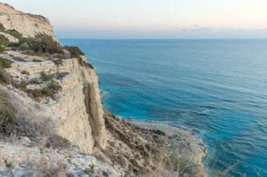 Kıbrıs kıyı şeridindeki bir uçurumdan deniz manzarası büyüleyici. Akdeniz 'in sakin güzelliğini gün batımında gösteriyor.