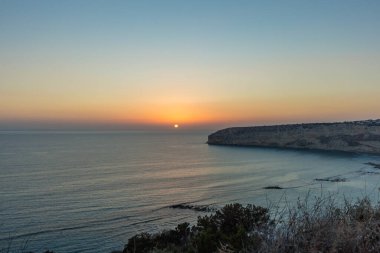 Kıbrıs 'taki Zapallo Körfezi Sahili' nde büyüleyici bir gün batımı, alacakaranlık batışı, dağın arkasında güneş batışı, çarpıcı bir akşam manzarası.