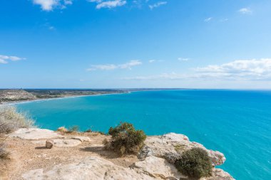 Güneşli bir günde Kıbrıs 'taki bir uçurumdan Akdeniz' in nefes kesen manzarasına hayret ediyorum. Ufuk, denizin engin genişliğine sonsuz bir şekilde uzanıyor. Huzurlu ve büyüleyici bir manzara yaratıyor.