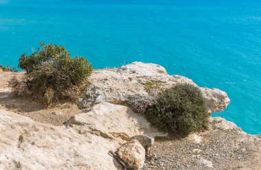Güneşli bir günde Kıbrıs 'taki bir uçurumdan Akdeniz' in nefes kesen manzarasına hayret ediyorum. Ufuk, denizin engin genişliğine sonsuz bir şekilde uzanıyor. Huzurlu ve büyüleyici bir manzara yaratıyor.