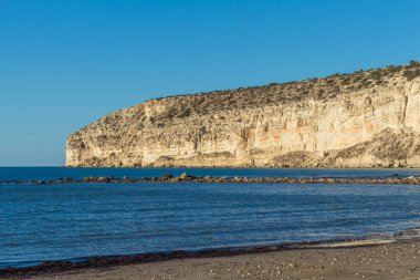 Kıbrıs 'taki Zapallo Körfezi Sahili' nin güzelliğini yaşayın kumlu kıyıları, denize dağılmış kayalar, güneşli bir günün sıcacık kucağında beyaz bir uçurum.
