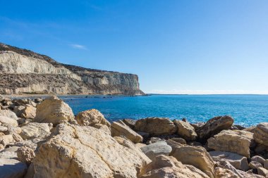 Kıbrıs 'taki Zapallo Körfezi Sahili' nin güzelliğini yaşayın kumlu kıyıları, denize dağılmış kayalar, güneşli bir günün sıcacık kucağında beyaz bir uçurum.