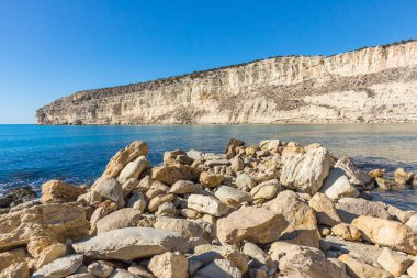 Kıbrıs 'taki Zapallo Körfezi Sahili' nin güzelliğini yaşayın kumlu kıyıları, denize dağılmış kayalar, güneşli bir günün sıcacık kucağında beyaz bir uçurum.