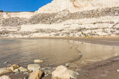 Kıbrıs 'taki Zapallo Körfezi Sahili' nin güzelliğini yaşayın kumlu kıyıları, denize dağılmış kayalar, güneşli bir günün sıcacık kucağında beyaz bir uçurum.