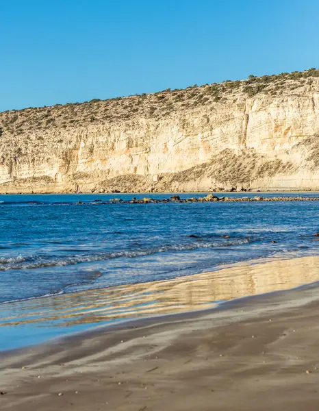 Kıbrıs 'taki Zapallo Körfezi Sahili' nin güzelliğini yaşayın kumlu kıyıları, denize dağılmış kayalar, güneşli bir günün sıcacık kucağında beyaz bir uçurum.