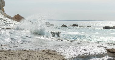 Kıbrıs 'ta kumsalda gün batımında taşlar, günışığında dalgalar.