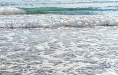 Kıbrıs 'ın kumlu sahillerinde dalgalar, güzel yaz deniz manzarası, deniz köpüğü ve kaya.