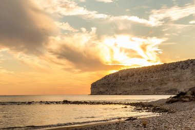 KKKTC sahilinde sıcak gün batımı, denizin üstünde kaya, atmosferik arazi manzarası