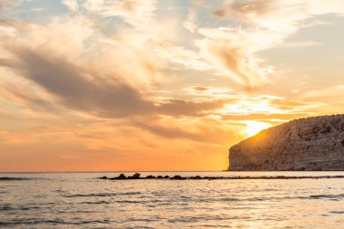 KKKTC sahilinde sıcak gün batımı, denizin üstünde kaya, atmosferik arazi manzarası