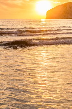 KKKTC sahilinde sıcak gün batımı, denizin üstünde kaya, atmosferik arazi manzarası