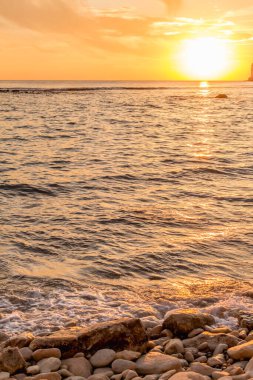 KKKTC sahilinde sıcak gün batımı, denizin üstünde kaya, atmosferik arazi manzarası