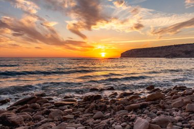 KKKTC sahilinde sıcak gün batımı, denizin üstünde kaya, atmosferik arazi manzarası