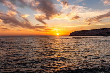 KKKTC sahilinde sıcak gün batımı, denizin üstünde kaya, atmosferik arazi manzarası