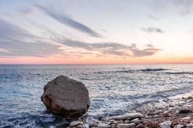 Dramatik uçurumlar, alacakaranlıkta yumuşak dalgalarla karşılaşır. Yalnız bir kaya bekçisi, dayanıklılık, yalnızlık ve doğal güzellik temalarını iletmek için idealdir.