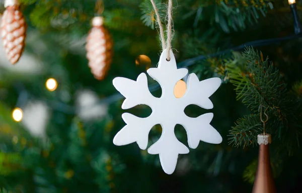 Köknar ağacının arka planında kar taneleri olan bir Noel süsü..