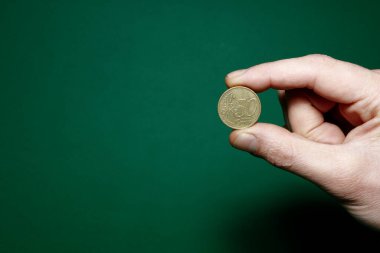 50 cent coin pinched with fingers on a green background