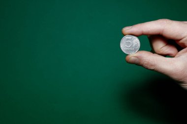 5 ruble coin pinched with fingers on a green background
