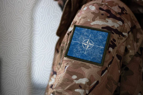 NATO askeri. NATO bayraklı asker, askeri üniformalı NATO bayrağı. Kamuflaj kıyafeti.