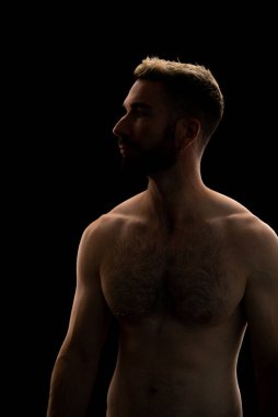 Siyah arka planda sakallı bir gencin portresi.