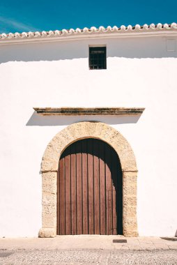 Ronda, İspanya - 23 Mayıs 2019: Eski bir İspanya kasabasında eski bir ahşap kapı ve beyaz bir ev duvarı