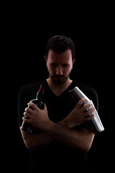 Siyah arka planda izole edilmiş viski ve karıştırıcıyla poz veren genç adam.