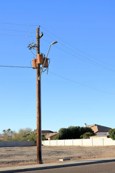 Electric utility street lighting pylon with attached lamp and three cylindrical transformers shot against blue sky background; copy space