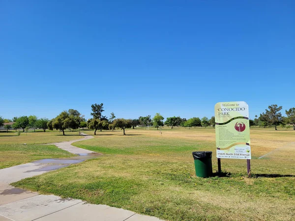 stock image Phoenix, AZ - May 6, 2023:  Paved path and City of Phoenix Welcome poster to Conocido Park that was established in 1978, a place of Disc Golf and ball games for local residents and their guests