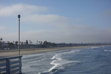 Rüzgârlı, serin bir sabah ve Pasifik sahilinin kumlu sahillerinde süzülen rahatlatıcı dalgalar tarihi bir ahşap kristal iskeleden görüldüğü gibi, San Diego, CA