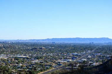 Bulutsuz gökyüzünün altında Arizona Capital City üzerinde öğleden sonra mavimsi bir sis bulutu var. Kuzey Dağ Parkı 'ndan Güney Dağları' na doğru.