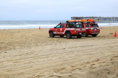 San Diego, CA - 13 Ağustos 2023: Can kurtaran ve itfaiye kırmızı renkli kamyonlar Pasifik Sahili 'nde park halindeki tarihi Crystal Pier' ın güneyine sabah, San Diego, California