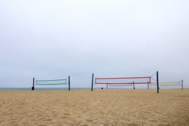 Güney Misyonu sahilindeki voleybol sahalarının renkli ağları sabah okyanus sisi ile kaplı, San Diego, California