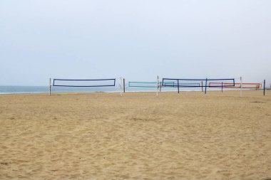 Colorful nets of volleyball courts at South Mission beach covered with morning ocean fog, San Diego, California clipart